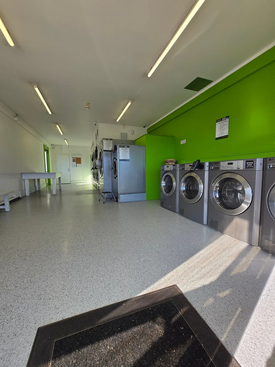 The Laundry Studio — modern front-load washers along the green feature wall